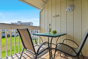 A balcony with a table, chairs, a bottle of wine, and a bowl of grapes. - Sandpiper Cove 8242 (Destin)