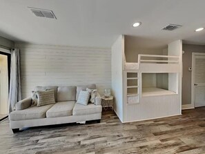 A room with a bunk bed, a sofa, and a small table. - Sandpiper Cove 8242 (Destin)