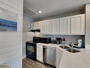 A kitchen with white cabinets, a black stove, a microwave, and a dishwasher. - Sandpiper Cove 8242 (Destin)