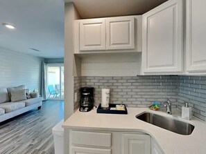 A modern kitchen with white cabinetry, a stainless steel sink, and a coffee maker. - Sandpiper Cove 8246 (Destin)