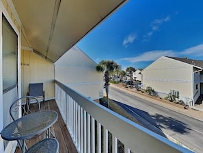 A balcony with a view of a street, a table, and a chair. - Sandpiper Cove 8246 (Destin)