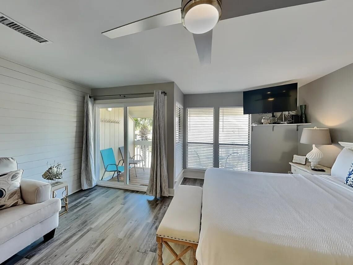 A hotel room with a bed, a desk, a chair, a TV, and a balcony with a view.