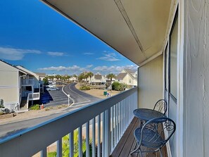 A balcony with a view of a residential street, a metal table, and chairs. - Sandpiper Cove 8246 (Destin)