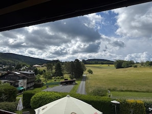 A hotel with a parking lot, a building with a sign, and a view of a green field and hills.