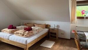 Makuuhuoneessa on puinen sänky, yöpöytä, pöytä tuoleineen ja ikkuna, josta avautuu näkymä vehreään maisemaan.