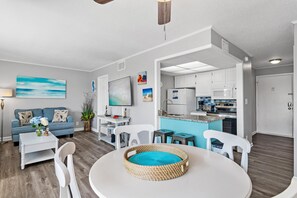 A modern living room with a sofa, coffee table, and a dining table with a woven centerpiece. - Sandpiper Cove 2015 (Destin)