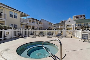 A swimming pool with a metal ladder, surrounded by a white fence and lounge chairs. - Sandpiper Cove 2015 (Destin)