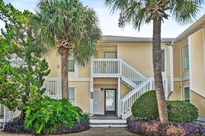 A residential building with a two-story structure, a front porch, and a staircase leading to the entrance. - Sandpiper Cove 2015 (Destin)