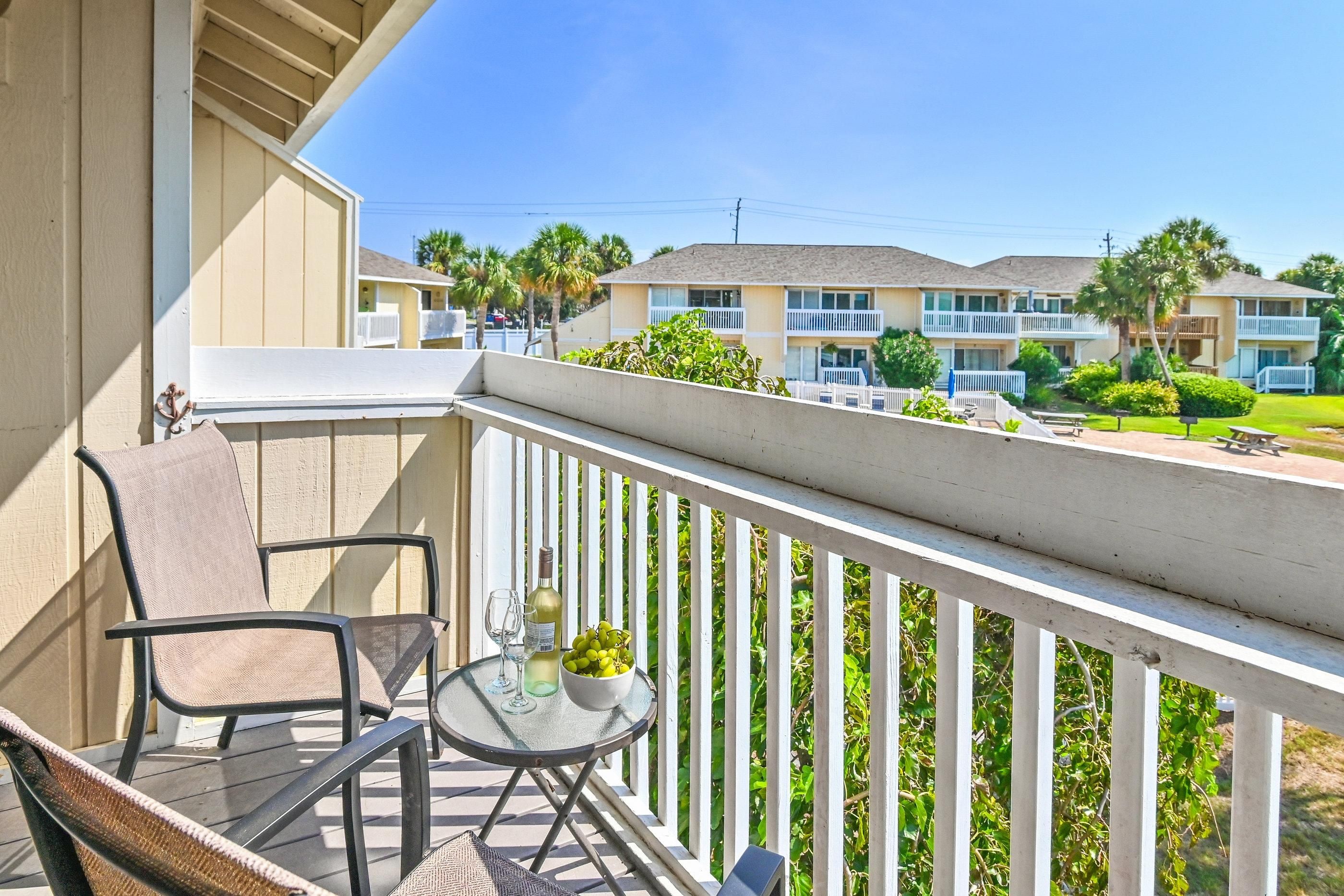 A balcony with a table, chairs, and a potted plant.