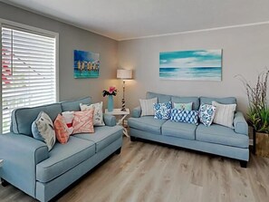 Ein Wohnzimmer mit zwei Sofas, einer Lampe und Wandbildern.