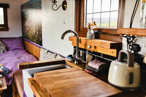 Uma cozinha compacta com bancada de madeira, pia e janela com vista para o exterior.