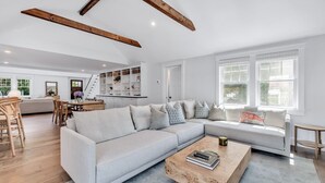 Amplia sala de estar con un sofá modular de colores claros, una mesa de centro de madera y una unidad de estanterías empotradas.