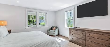 A bedroom with a bed, a chair, a TV, and a wooden dresser.