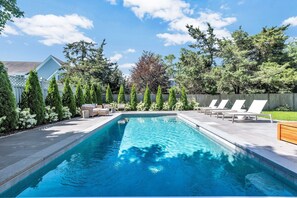 A rectangular swimming pool with a clear blue water surface, surrounded by a wooden deck. - Elevated Osterville Escape with Heated Pool RPAM128 (Osterville)