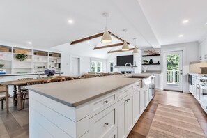 A spacious kitchen with a large island, white cabinetry, and pendant lighting. - Elevated Osterville Escape with Heated Pool RPAM128 (Osterville)