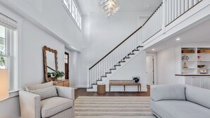 Un espacio habitable amplio con escalera, un sofá, un banco y un espejo decorativo.
