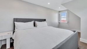 Un dormitorio con cama, mesita de noche y ventana con persianas.