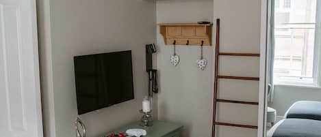 Un dormitorio con cama, cómoda, reloj en la pared, televisor y ventana.