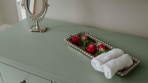 Une coiffeuse verte avec un miroir, un plateau orné de roses rouges et une serviette blanche pliée.