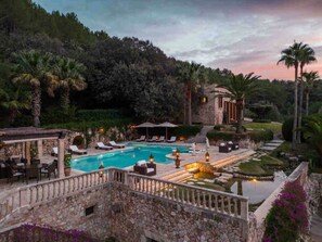 A pool area with lounge chairs, a stone structure, and a landscaped garden. - The Dream Valley of Mallorca (Pollença)