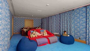 A room with a red sofa, blue bean bags, patterned wallpaper, and a small round table. - The Dream Valley of Mallorca (Pollença)