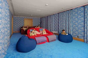 Ein Zimmer mit einer roten Couch, blauen Sitzsäcken, gemustertem Wandpapier und einem kleinen runden Tisch.