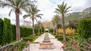 A stone pathway leading to a gazebo in a landscaped garden with palm trees and hedges. - The Dream Valley of Mallorca (Pollença)