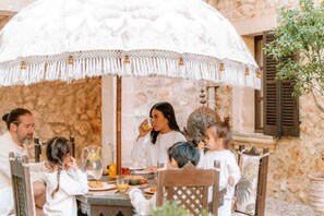 A family dining outdoors under a large, ornate umbrella. - The Dream Valley of Mallorca (Pollença)