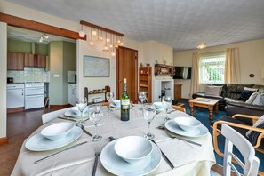 A dining area with a table set for four, a bottle of wine, and a map on the wall. - Anglesey Country Retreat (Amlwch)