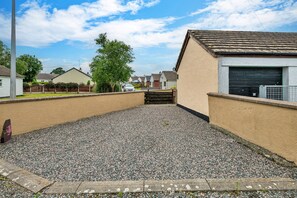 A gravel driveway leading to a residential property with a garage and a white car parked nearby. - Anglesey Country Retreat (Amlwch)