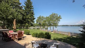 A patio with outdoor furniture, a fire pit, and a view of a lake with boats.