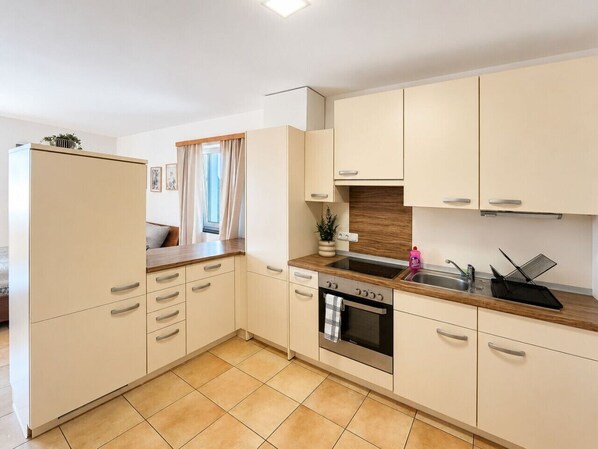 A modern kitchen with white cabinets, a wooden countertop, a built-in oven, and a sink.