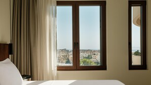 Habitació d'hotel amb un llit, una finestra i vista a una ciutat, i una cortina.