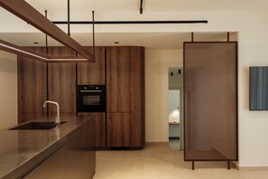 A modern kitchen with wooden cabinetry, a built-in oven, and a sleek countertop. - Linum Hill Elegant 2BR Apt with Sea View & Pool (Agios Nikolaos)