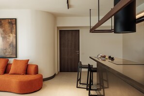 A modern kitchen with a dark wooden door, a bar area with stools, and a large abstract painting on the wall. - Linum Hill Elegant 2BR Apt with Sea View & Pool (Agios Nikolaos)