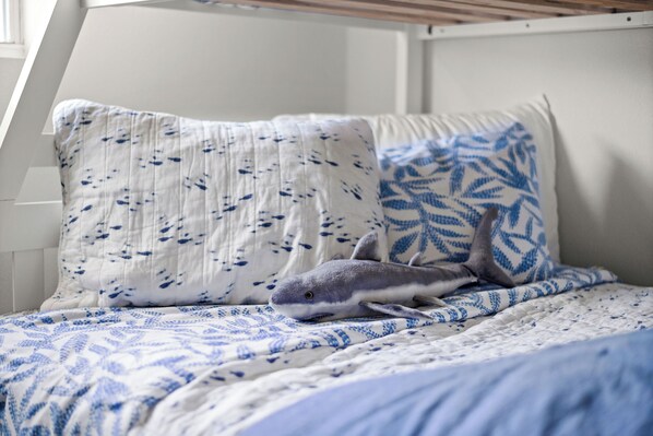 A bed with a patterned blue and white bedding, a pillow with a leaf design, and a plush shark toy. - Steps to the Beach & Bocce Ball (Redington Beach)