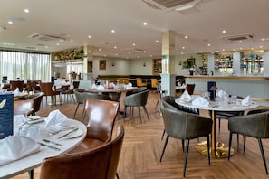 A restaurant with round tables, leather chairs, and a bar area. - Resort Chalet Near Golf (Cambridge)