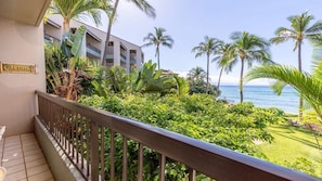 A balcony with a view of a tropical garden and the ocean.