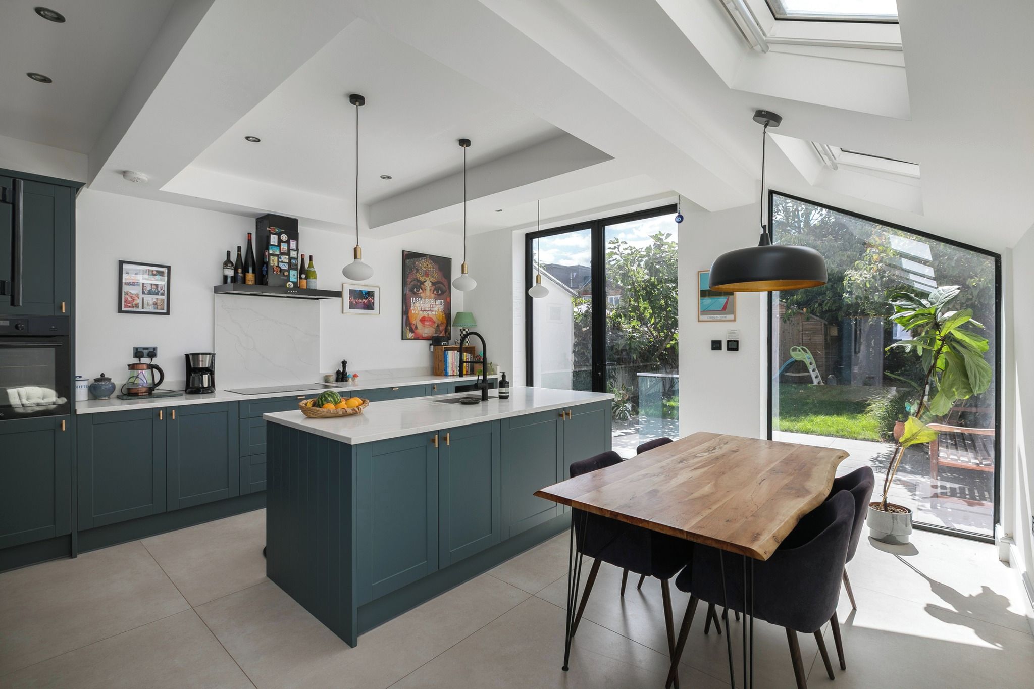 Een moderne keuken met een groot eiland, donkere kastjes en een eethoek met een houten tafel en stoelen.