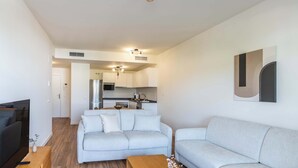 Ein modernes Wohnzimmer mit einem grauen Sofa, einem Holztisch und einem Fernseher.