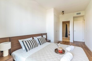 Une chambre d’hôtel avec un lit, une table de chevet, une lampe, un plateau de fraises et un peignoir.