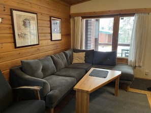 Une pièce chaleureuse avec un canapé, une table basse en bois et des tableaux encadrés accrochés au mur.