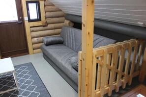 A log cabin interior with a sofa, a small table, and a wooden playpen. - Onnela 2 Chalet | Private Sauna & Fireplace | Ruka (Kuusamo)