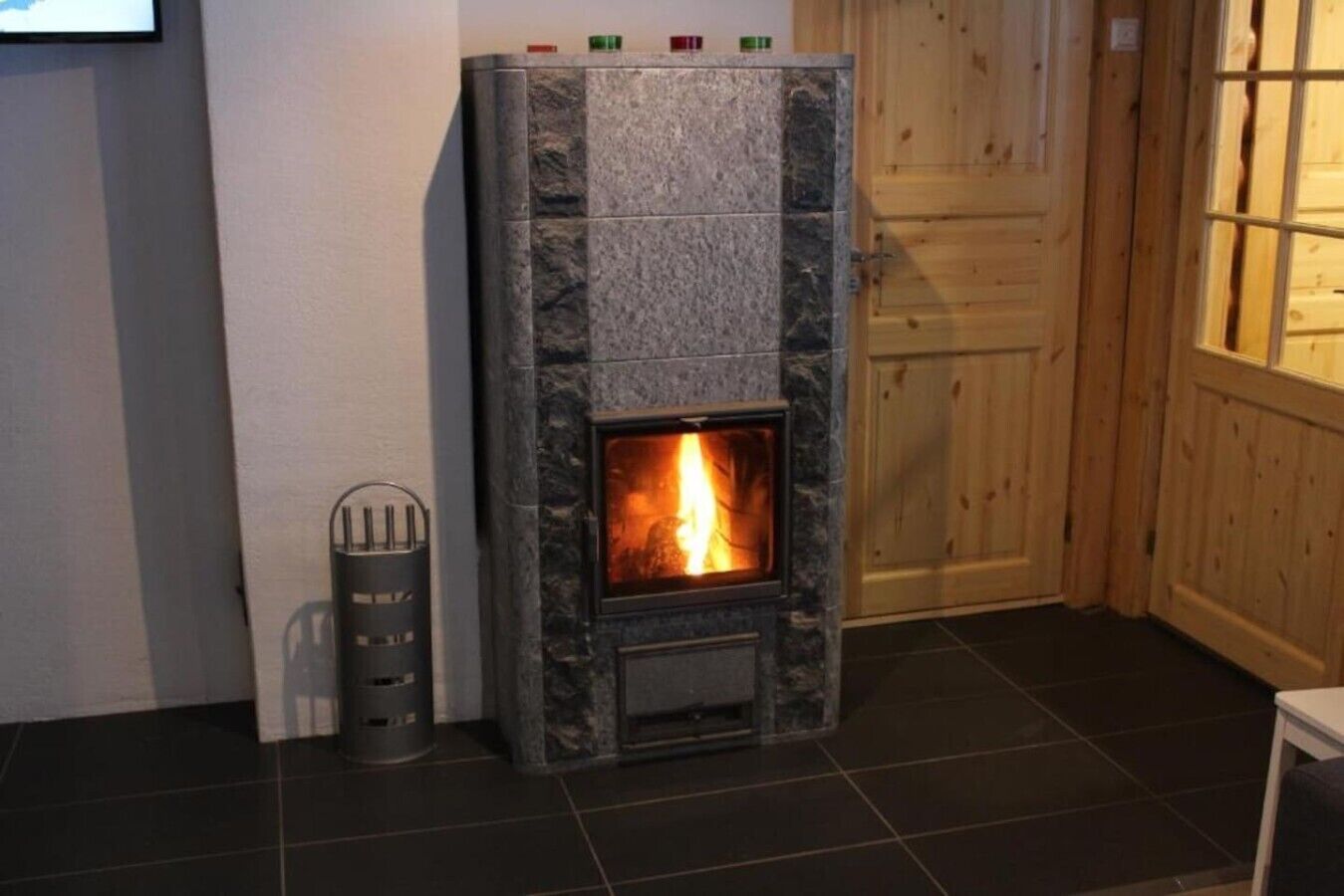 A stone fireplace with a visible fire, a metal ashtray, and a wooden door in the background.