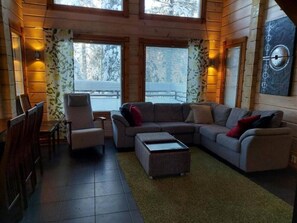 Ein gemütliches Wohnzimmer mit einer Eckcouch, einem kleinen Tisch und einem Sessel.
