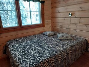 Ein Zimmer mit einem Bett, einem Fenster und Holzwänden.