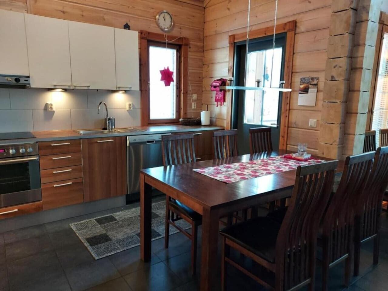 Un interior de madera con cocina, comedor y un reloj en la pared.