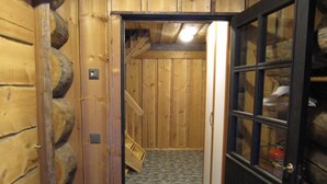 Corredor interno de madeira com uma porta que dá para um quarto.