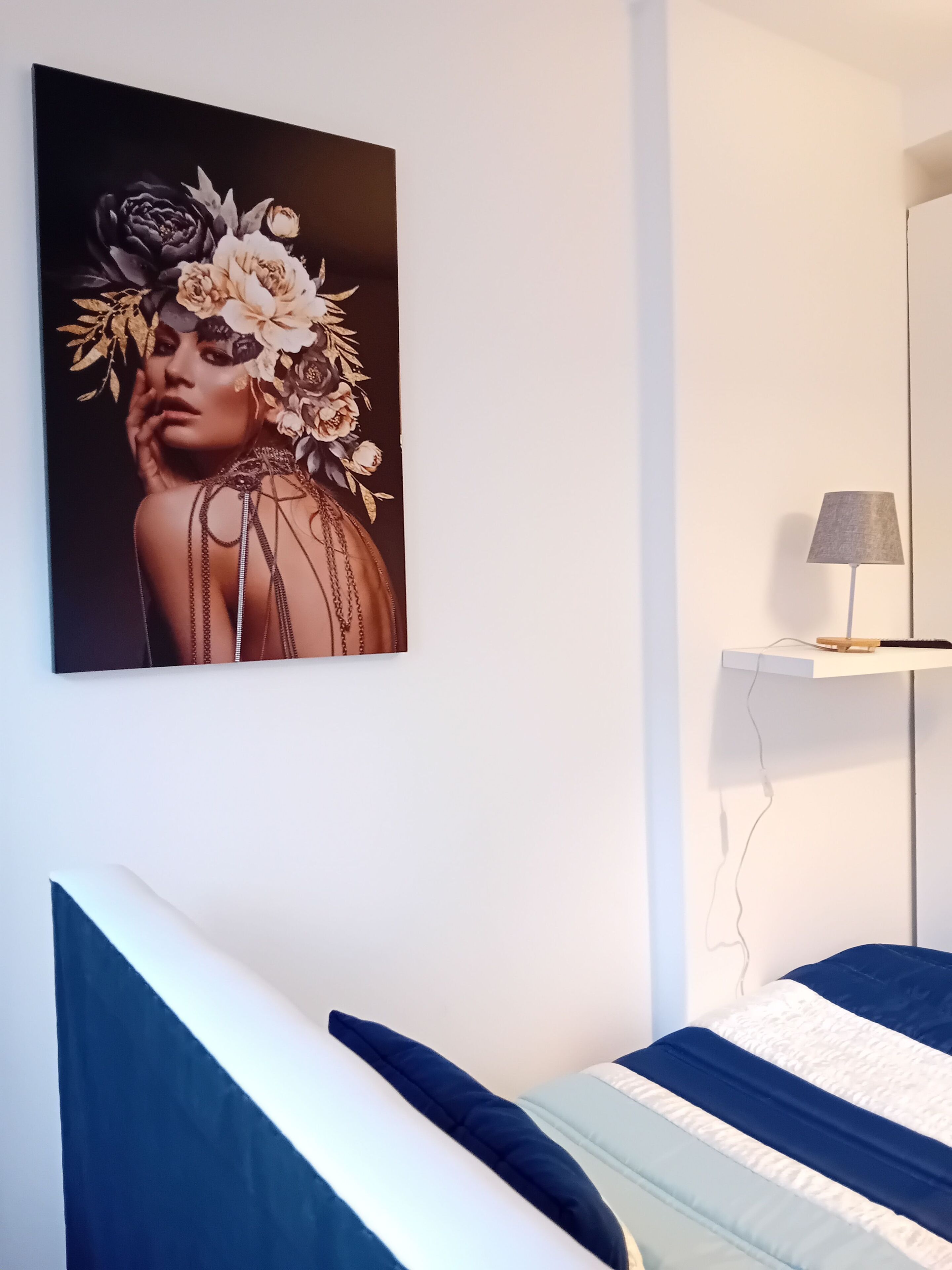 Un dormitorio con una cama, una lámpara de pared y una obra de arte enmarcada.
