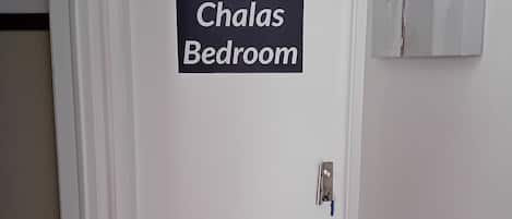 Een deur met een bord waarop staat 'Chalas Bedroom', dat de naam van de kamer aangeeft.